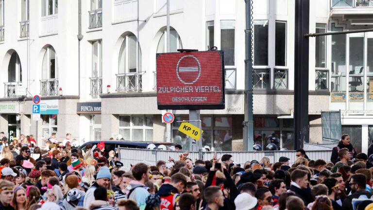 30266387-zahlreiche-karnevalisten-stehen-an-einer-absperrung-da-polizeibeamte-den-zugang-zur-zuelpicher-strasse-wegen-ueberfuellung-abgeriegelt-haben-2tvUWl1Vr8ea