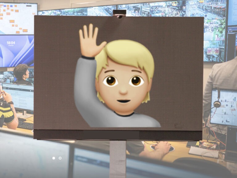 A raised-hand message on a large LED screen in an event control room